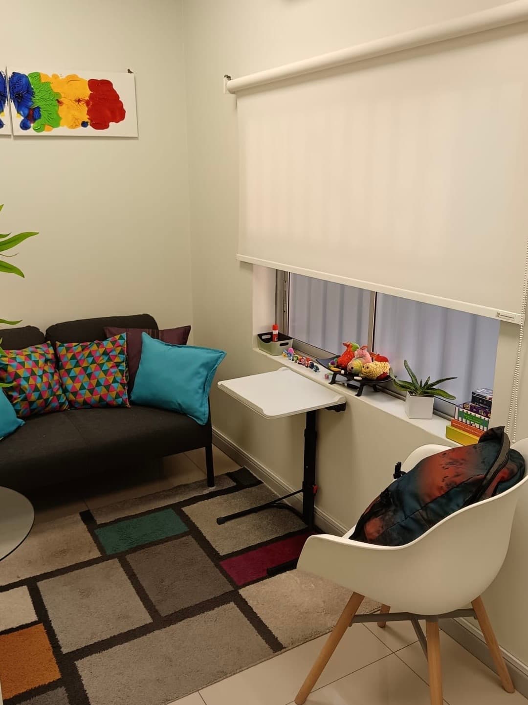 Sala de atención con sofá, sillón de trabajo y ventana luminosa con materiales terapéuticos